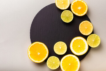 Citrus fruits - lemon, orange and lime on black stone desk on grey background from above. Healthy sweets. Natural vitamins from fruits