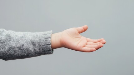 Young child's hand reaching out against a neutral gray background showing innocence and curiosity