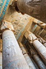 Vertical view of the columns and the colorful ceiling of the temple of Dendera, Egypt. Hator goddess faces at the capital of each column.