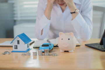 An anxious employee sits at a desk calculating taxes and mortgage payments, stressed about debt,...