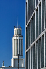 Fragment of the facade of a modern office building and a tower of a historic, modernist building in Poznan