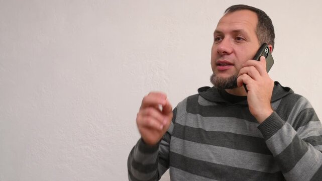 A bearded man talking on the phone proves, convinces the interlocutor