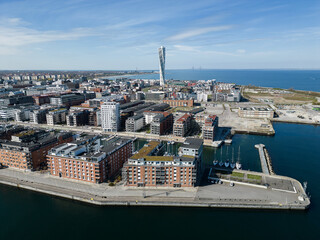 Aerial view of Turning Torso skyscraper rising above the cityscape, contrasting with the calm blue sea and modern architecture, MalmÃ¶, SkÃ¥ne lÃ¤n, Sweden.