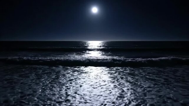 Bright moon reflecting on the dark ocean at night. A shimmering moonlight path on the water as waves roll onto the beach. Natural nighttime seascape