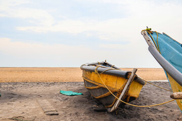 Old row boat on the beach shore during sunrise. Wooden fishing boat, nature landscape.