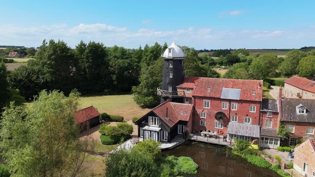 Ariel footage of Burnham Overy Staithe Mill in Norfolk England on the river Burn. Overy Water Mill, Windmill. Rural summer scene.