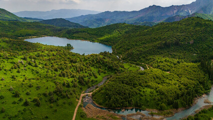 Aerial view of Sary-Chelek Lake in Kyrgyzstan. Deep blue alpine water surrounded by forested mountains and golden valleys within a pristine biosphere reserve