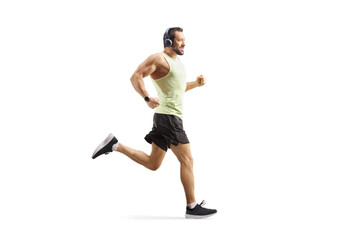 Full length profile shot of a man with headphones jogging