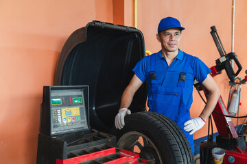 Mechanic in Blue Uniform Holding Tire in Tire Workshop with Modern Equipment and Tools for Vehicle Maintenance and Repair Services