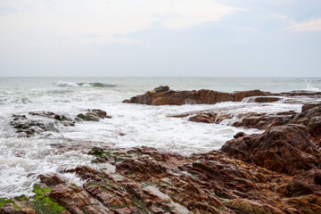Obraz premium Old rocks on the seaside. Beautiful background of beach water flowing on the rocks.