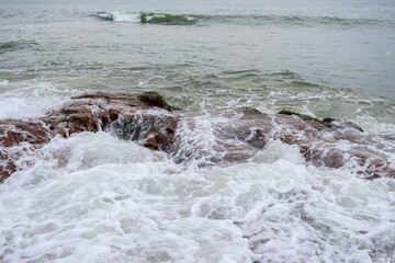 Old rocks on the seaside. Beautiful background of beach water flowing on the rocks.
