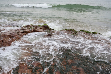 Old rocks on the seaside. Beautiful background of beach water flowing on the rocks.
