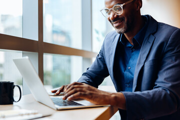 Businessman working on laptop at brightly lit office desk