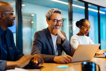 Professionals at a table working on laptops during a meeting