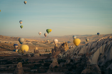 Goreme, Turkiye - 11 October 2019: View of a serene sunrise paints the sky as hot air balloons float over the rugged landscape of Cappadocia.