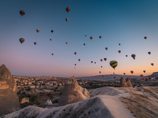 Goreme, Turkiye - 10 October 2019: View of countless hot air balloons drifting silently over the dreamy landscape of Cappadocia, as the first light paints the sky with hues of pink and gold.