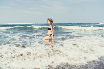 Fototapeta premium Joyful woman leaps in waves, symbolizing freedom, vitality and conscious rejection of digital overwhelm in favor of pure, offline connection with the body.
