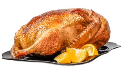 Whole roasted duck with crispy golden skin served on a platter with lemon slices isolated