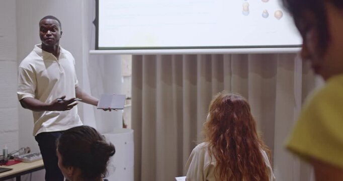 Multiracial business team in a training presentation at a small modern indoor amphitheater. A diverse group of colleagues listen attentively during a business meeting.
