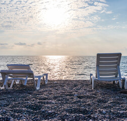 Fototapeta premium Set of white plastic patio chaise lounge at the beach. Outdoors