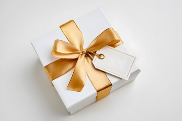 White gift box with golden ribbon and blank tag on a light background ready for special occasions