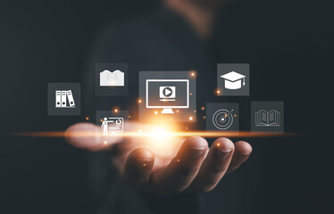 Businessman holding virtual e-learning icons such as video courses, books, and graduation cap, concept of online education, digital learning, and modern technology for professional development.