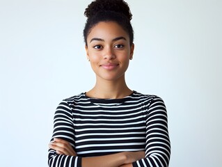 Photo of a young woman in a striped shirt smiling confidently with crossed arms