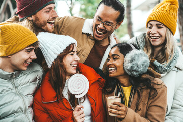 Happy friends having fun drinking mulled wine and hot chocolate at Christmas Market - Cheerful...