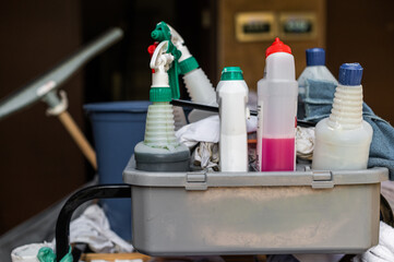 Cleaning supplies organized in a cart during a busy cleaning session in an office building hallway