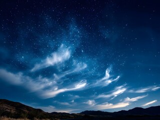 Naklejka premium A breathtaking deep blue black night sky filled with countless twinkling stars and delicate wispy clouds stretching across the vast celestial expanse
