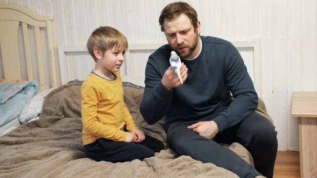 Father and son enjoying at home. Young boy and his daddy playing with funny pet budgerigar parrot. Happy family. Tamed budgie parakeet. People take care of and play with bird. Cute domestic animals