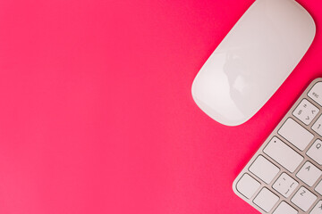 Clean creative workspace layout with a compact keyboard and wireless mouse on a bright pink...