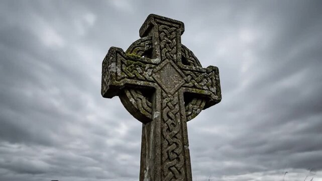 Ancient moss-covered Celtic cross stands against a dramatic, overcast sky