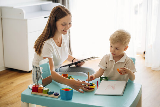Playing with toys, motor skills. Speech therapist is with young boy indoors