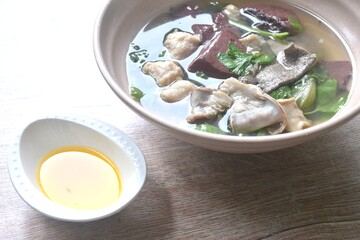 boiled pork blood and entrails with chop pork topping lettuce in soup on bowl dipping spicy sour chili sauce 