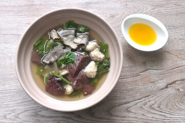 boiled pork blood and entrails with chop pork topping lettuce in soup on bowl dipping spicy sour chili sauce 