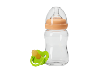 Isolated set of baby pacifier with green handle and feeding bottle on a light surface