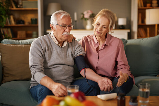 An elderly couple is sitting on their living room couch. - Powered by Adobe