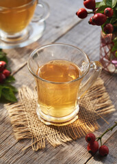 A cup of rose hip tea with fresh berries on a wooden table