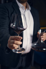Sommelier offering glass of red wine with calm confidence. Concept of hospitality, mindfulness, and refined communication in luxury service with emotional warmth.