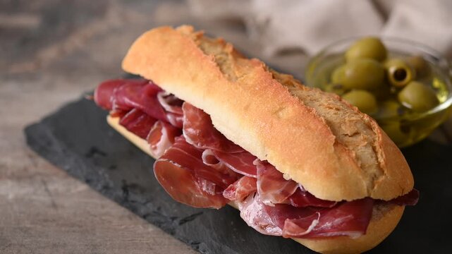Spanish serrano ham sandwich on wooden table. Spanish bocadillo de jamon serrano