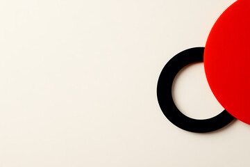 Abstract art featuring a bold red disc partially intersecting with a sleek black ring against a neutral backdrop, creating a minimalist and modern composition.