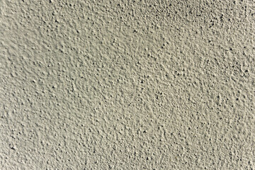 Rough light grey concrete wall texture with porous surface.