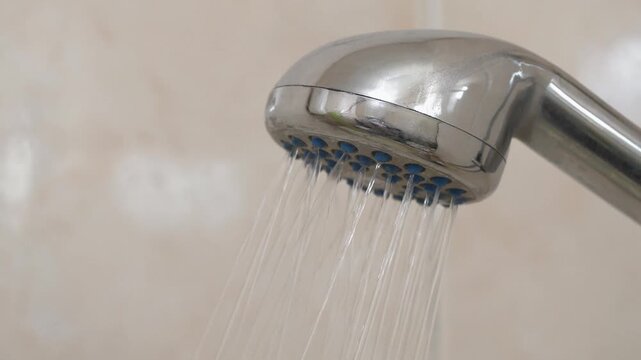 Water flows out of shower head with sound. Shower head in bathroom. Cinema 4K video with sound