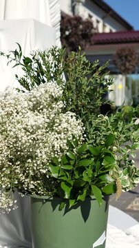 Flowers in a plastic bucket in the wind on the street to create a wedding arrangement and flower arch. gypsophila, ruscus