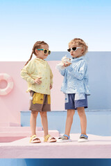 Two cheerful children playing outdoors in colorful summer outfits by the beach.