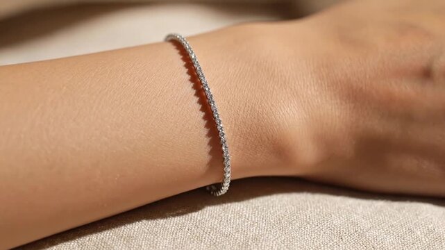 Close-up of a shimmering diamond tennis bracelet on a slender female wrist.