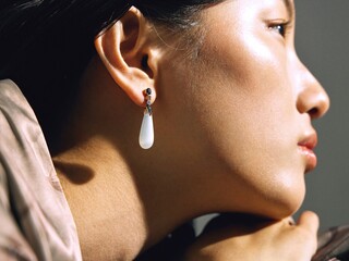 Elegant woman in a soft pink top with statement earrings, captured in a modern setting.