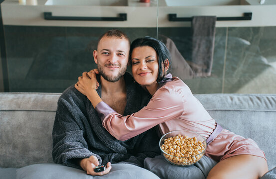 A content couple, wrapped in comfort, chats amicably in their modern home, creating a serene and warm morning together.