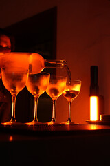 Four coupe cocktail glasses lined up on a dark, textured bar surface. Orange and red backlight, creating an atmospheric and sophisticated nightlife scene
